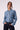 Brunnette woman wearing a blue tencel button down shirt on a white background.